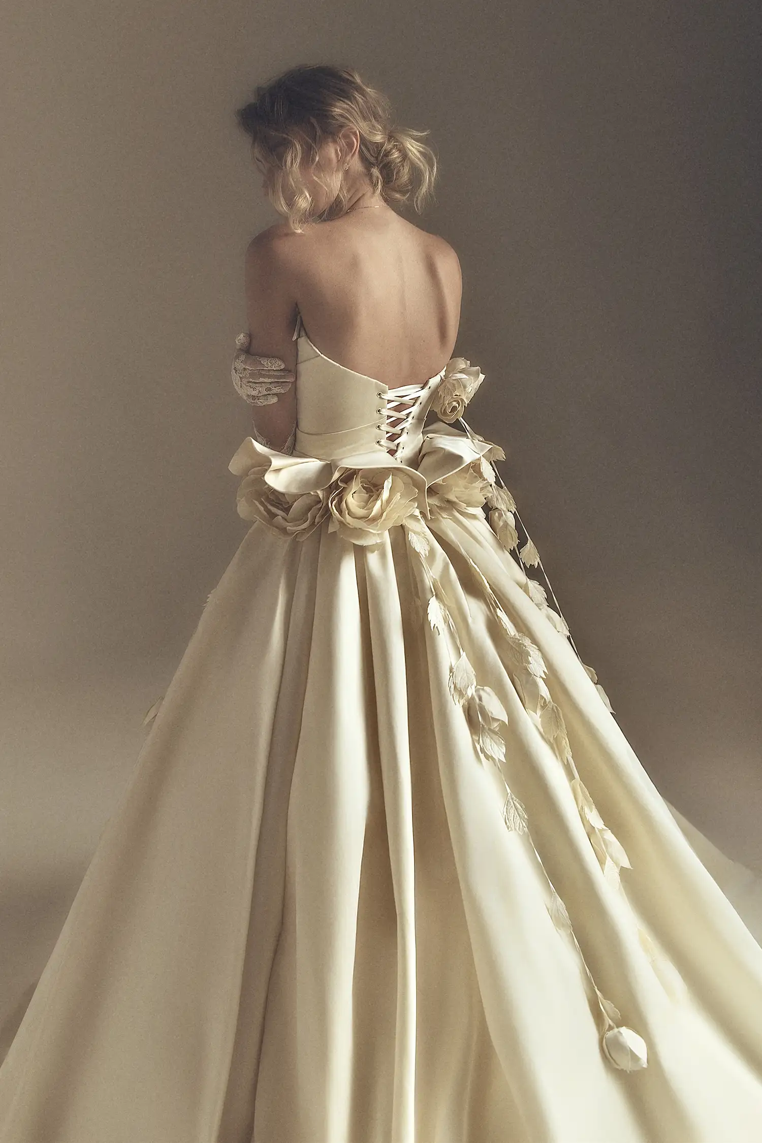 Strapless satin ballgown with draped bodice, ruffled basque, and handmade satin roses at neckline and waist.