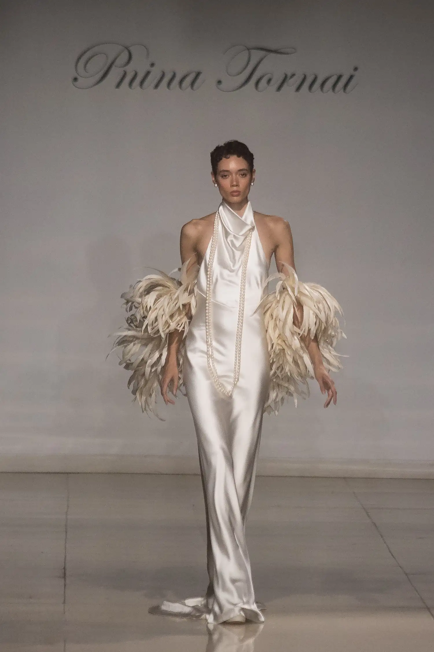 Bias cut satin halter gown with low back, shown with rooster feather boa.