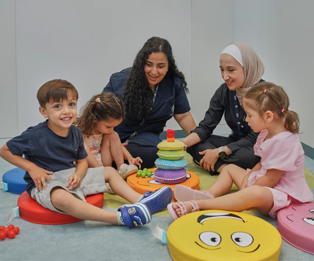 Two therapists engaging with three young children during a group therapy session at Seeds of Hope Center