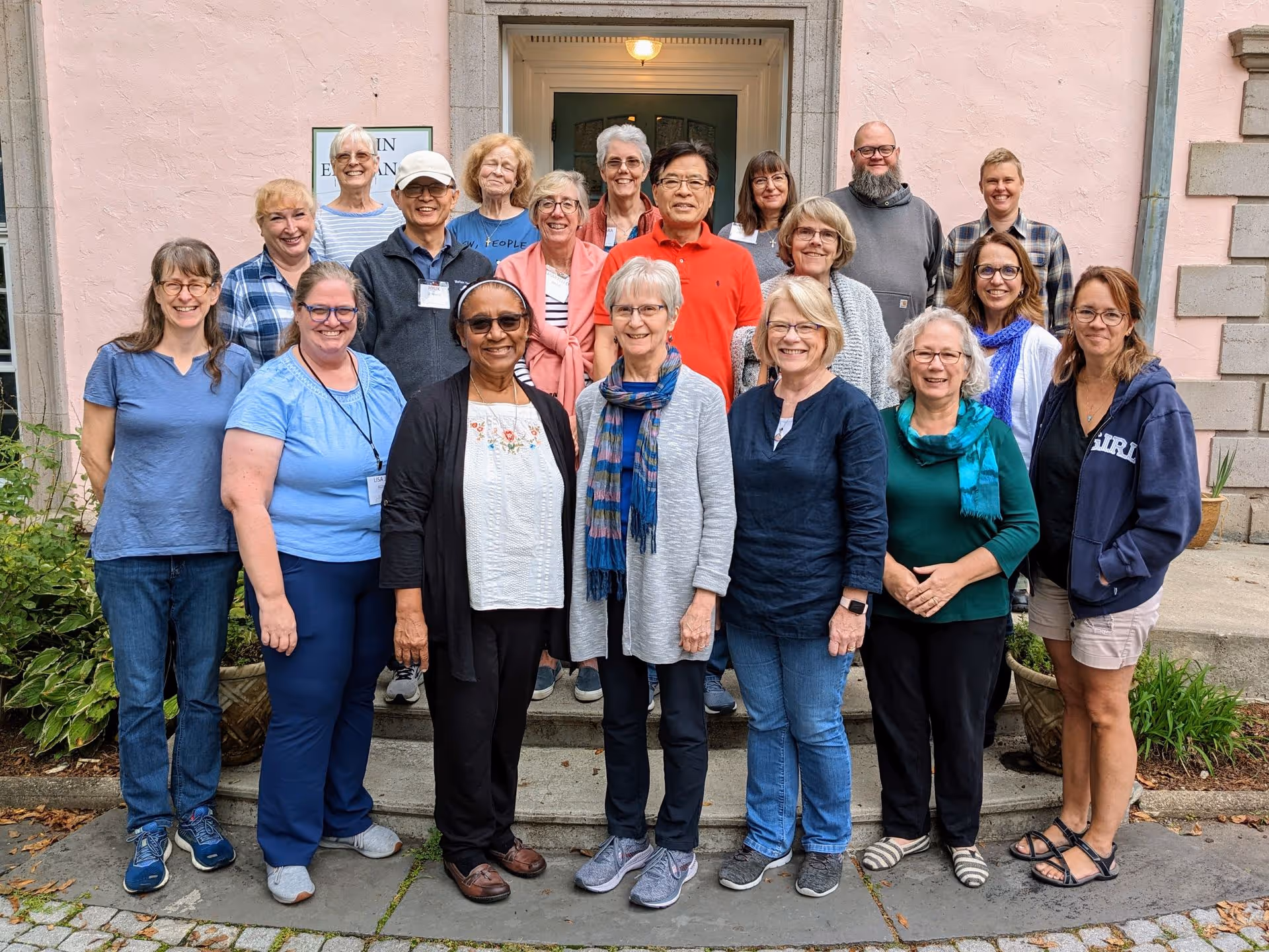 A group of Gateways to God participants stand together on the steps in front of the main entrance to Rolling Ridge