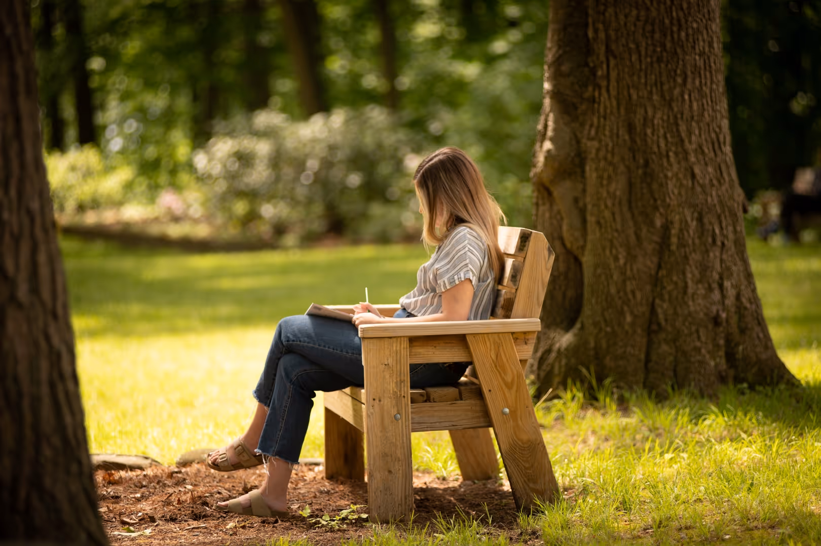 A woman sits on a bench at Rolling Ridge and writes in a journal