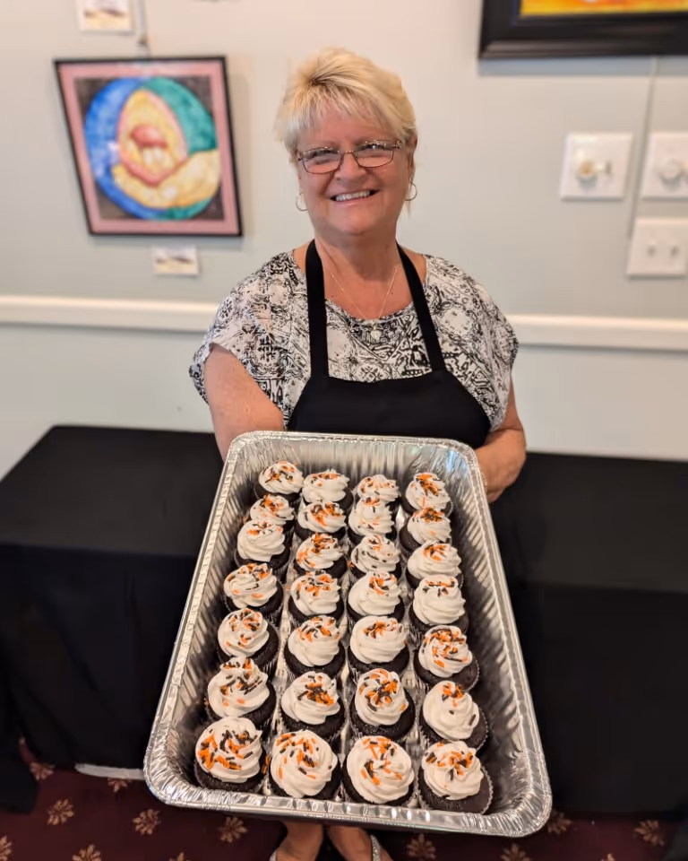 Rolling Ridge chef holds a sheet pan of decorated cupcakes
