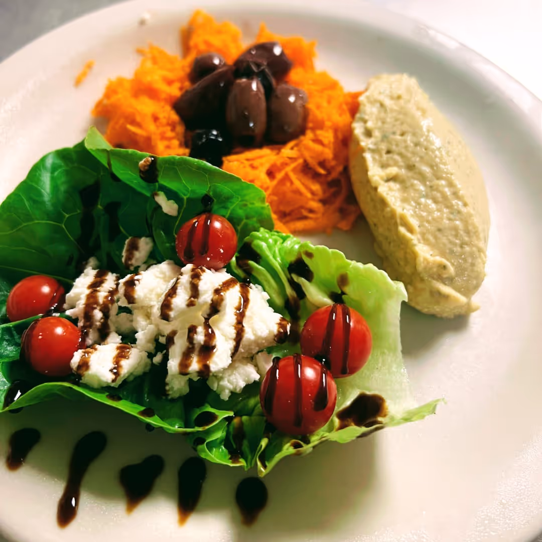 An image of a hummus, feta, and tomato salad, prepared by chefs at Rolling Ridge