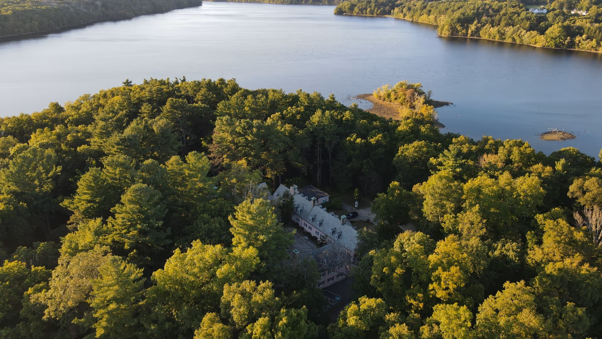 An arial photograph of the Rolling Ridge peninsula with the house peaking through the trees in the center of the shot 
