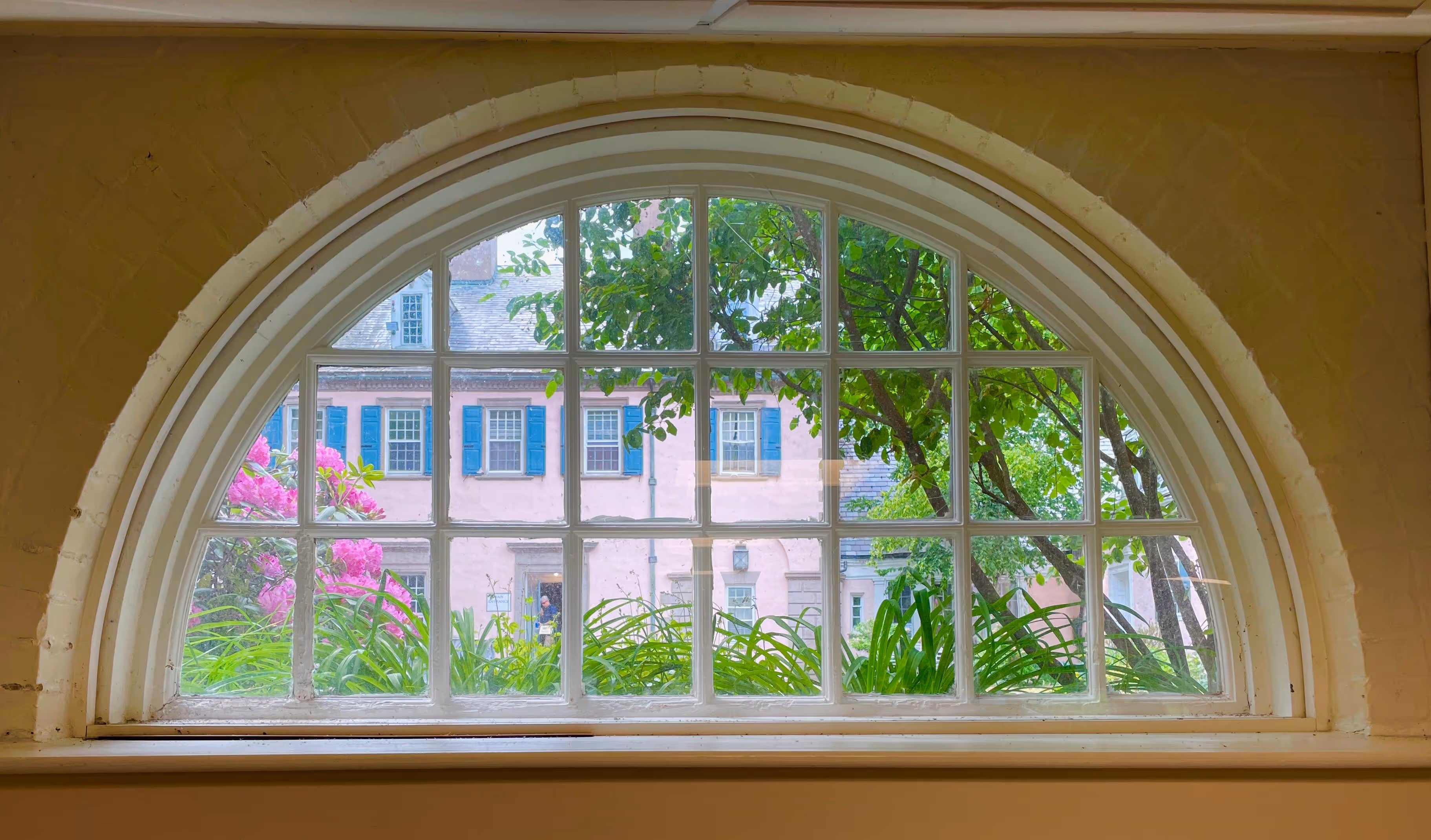 A photo from inside Moses Hall looking out of a half circle window into the Rolling Ridge courtyard