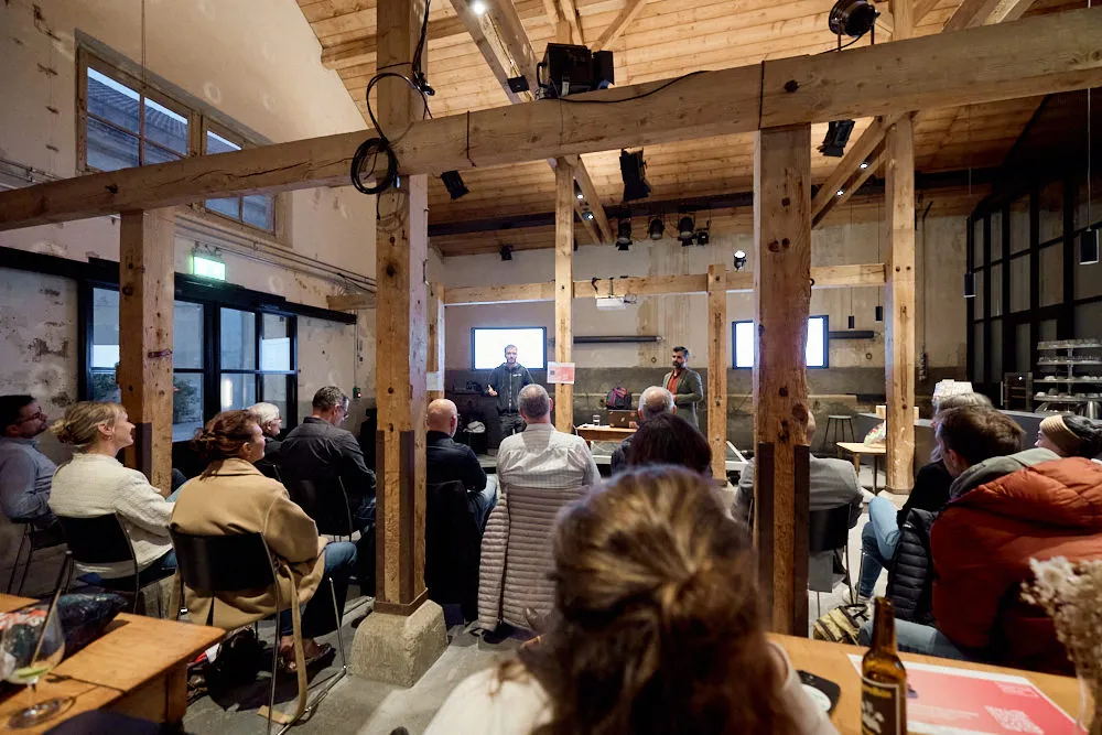 Zwei Männer halten vor einem sitzendem Publikum eine Präsentation.