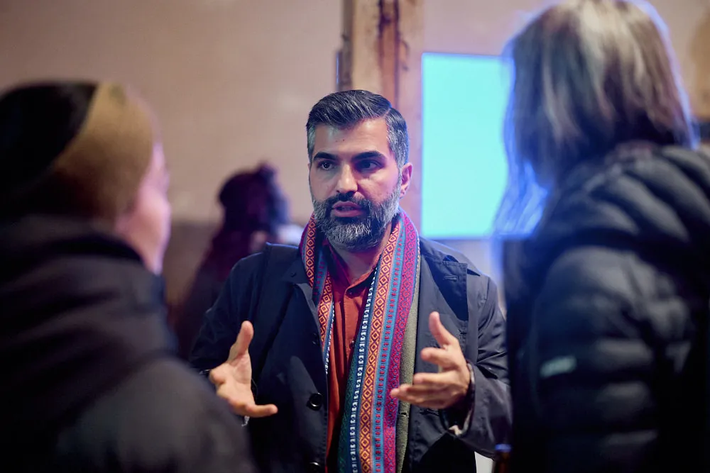 Ein Mann spricht mit zwei Frauen. Sie tragen dicke Jacken.