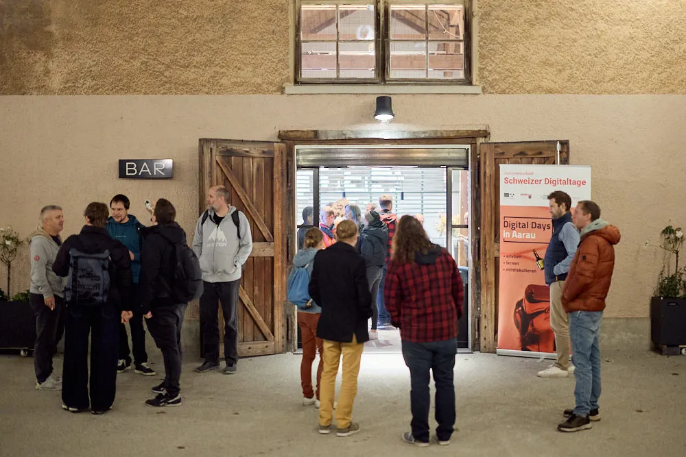 Mehrere Menschen stehen vor einem Gebäude mit geöffneten Türen.
