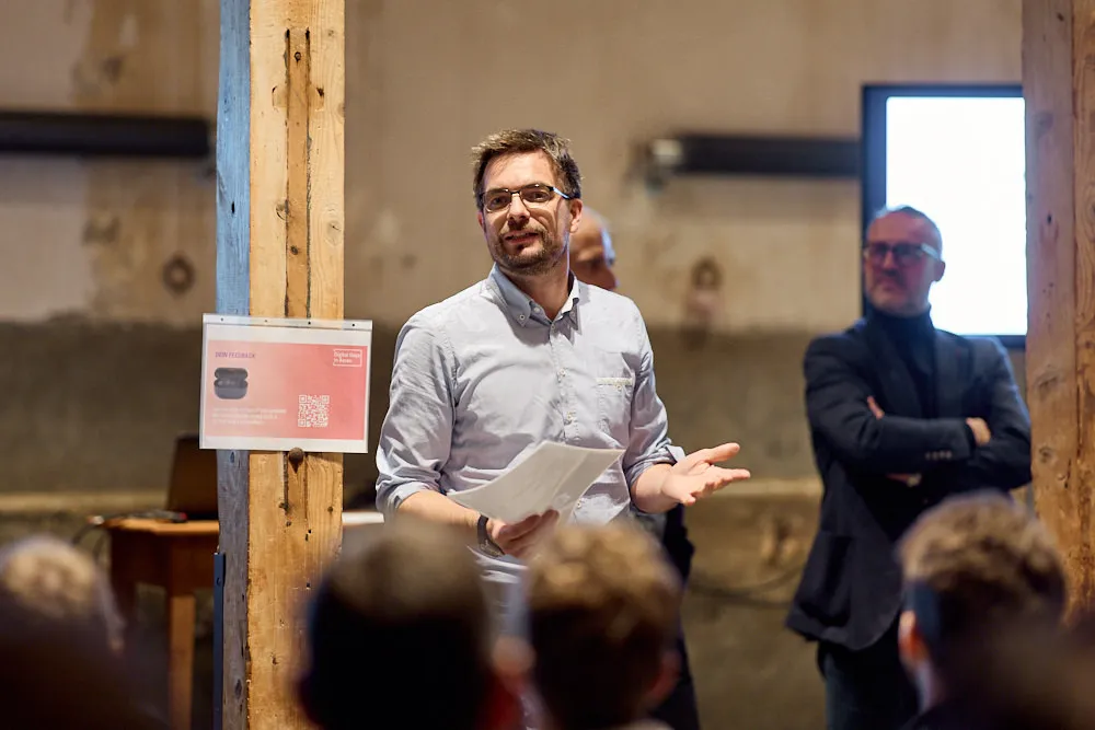 Ein Mann hält lächelnd eine Präsentation.