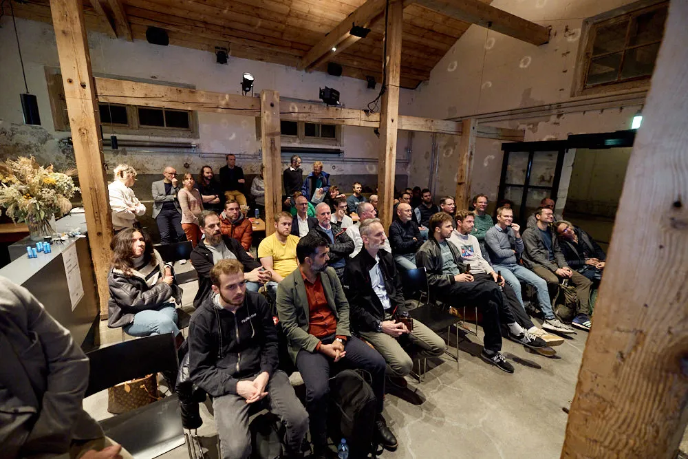 Ein Publikum mit vielen Menschen hört gespannt zu.