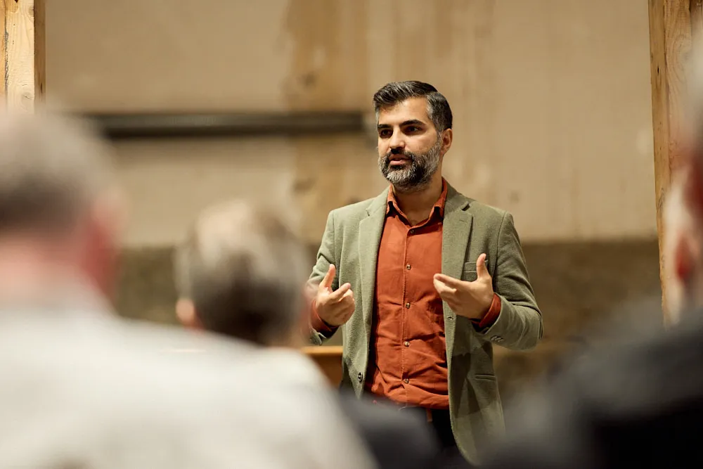 Ein Mann spricht vor einem Publikum und gestikuliert mit seinen Händen.