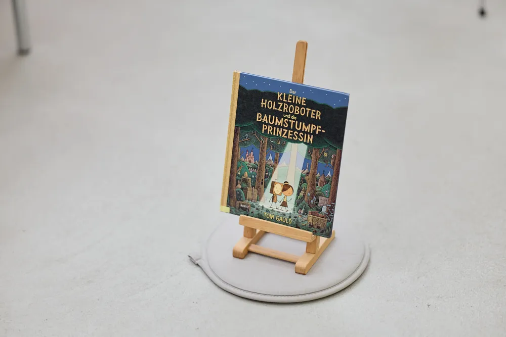 Ein Kinderbuch steht auf einer kleinen Staffelei auf dem Boden.