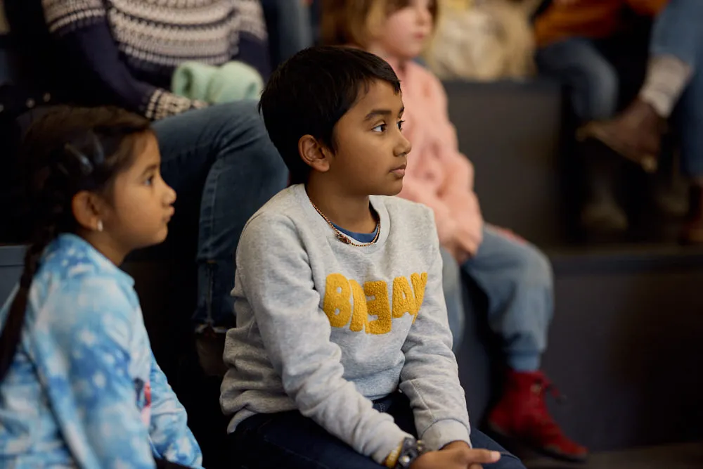 Ein kleines Mädchen und ein kleiner Junge im Publikum hören gespannt zu.