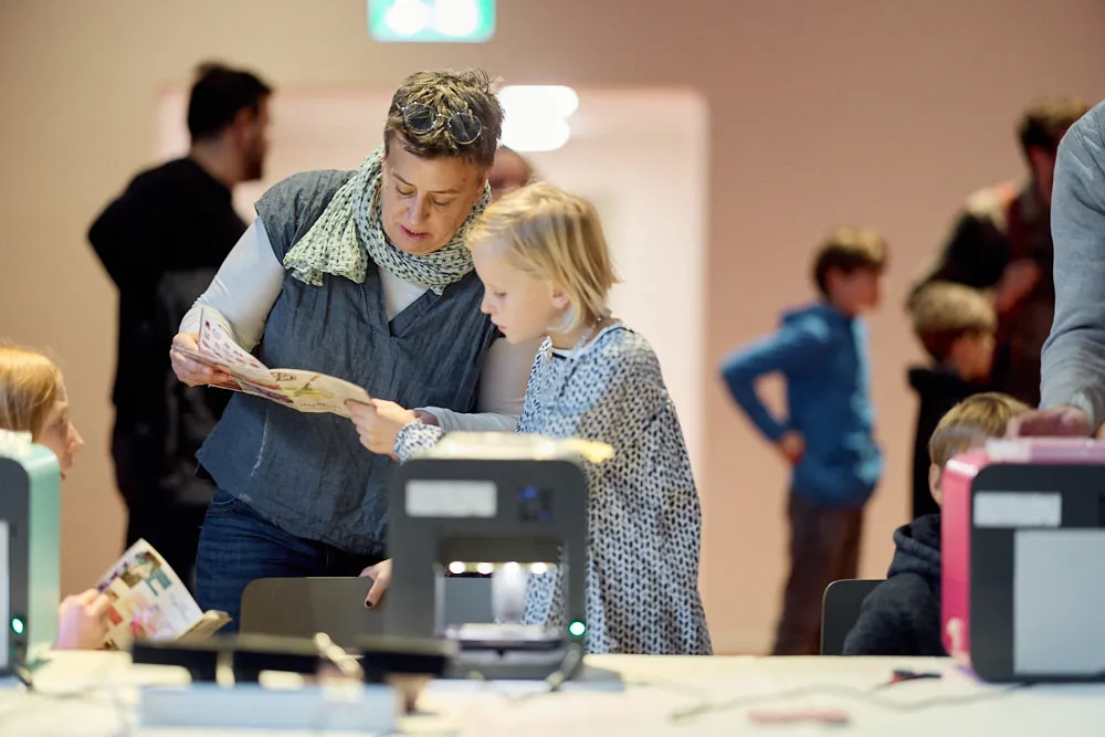 Eine Frau liest mit einem Mädchen ein Heft.
