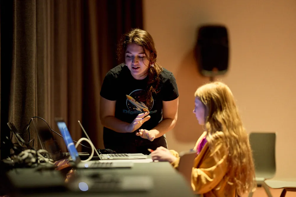 Eine Frau erklärt einem Mädchen am Laptop etwas.