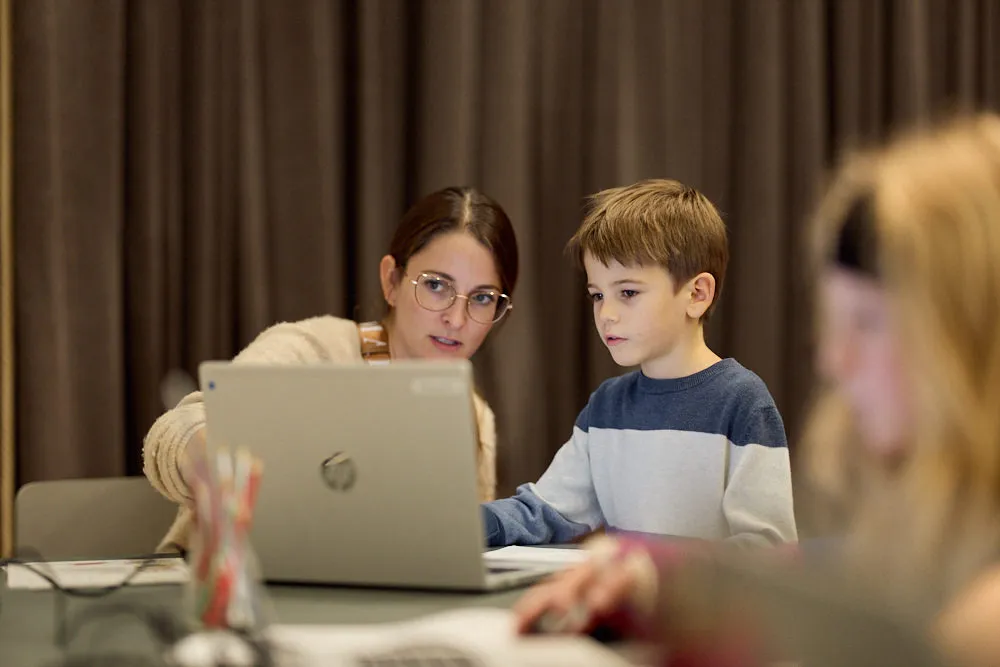 Eine Frau und ein Junge schauen in einen Laptop.