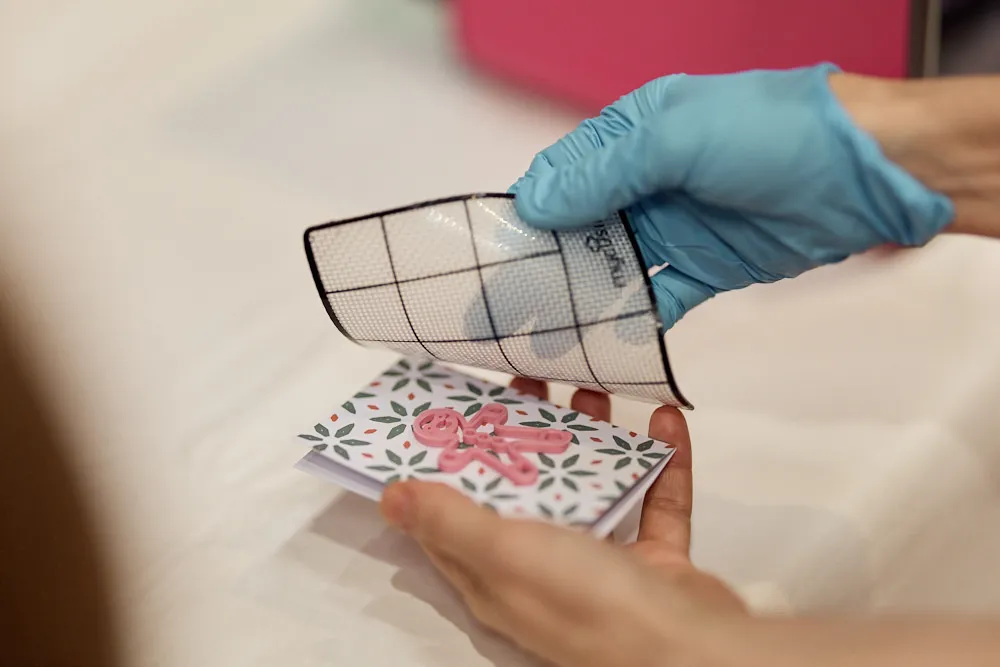 Zwei Hände halten eine Karte mit einem 3D-gedruckten Männchen.