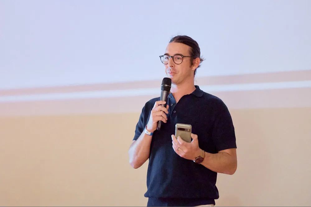 Ein Mann hält in der linken Hand ein Smartphone und in der anderen Hand ein Mikrofon.