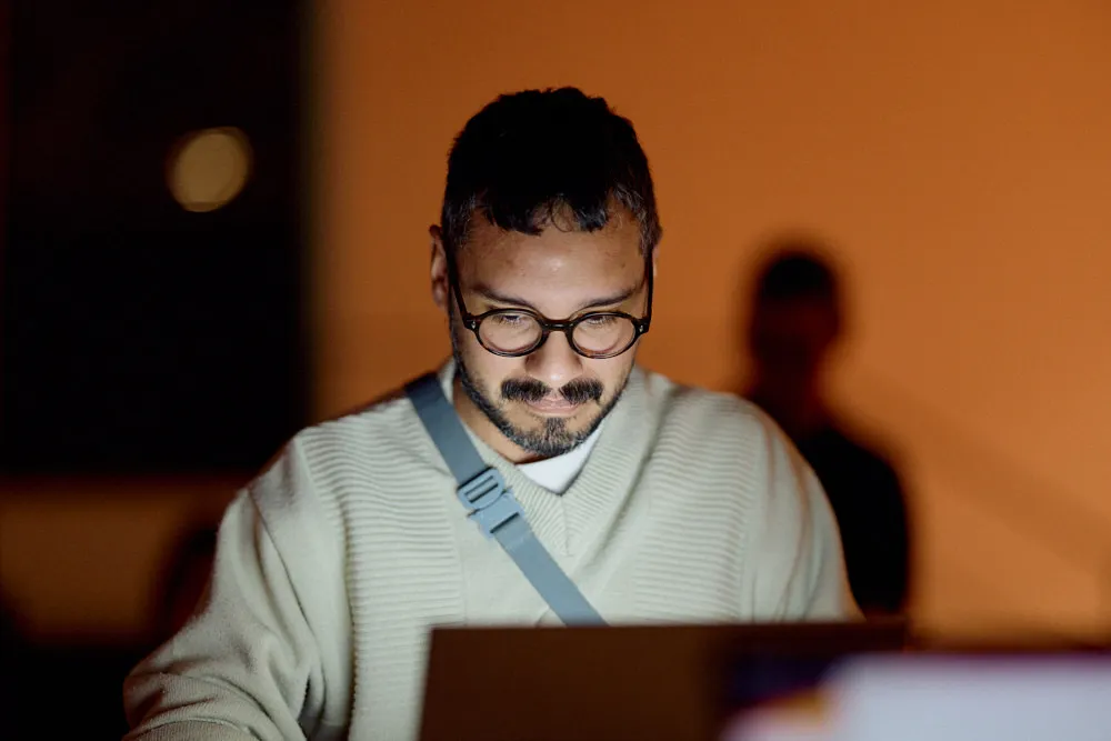 Ein Mann schaut in einen beleuchteten Bildschirm von wahrscheinlich einem Laptop.