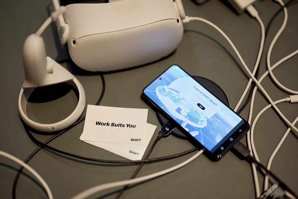 Eine VR-Brille, ein Smartphone und kleine Karten befinden sich auf einem Tisch.