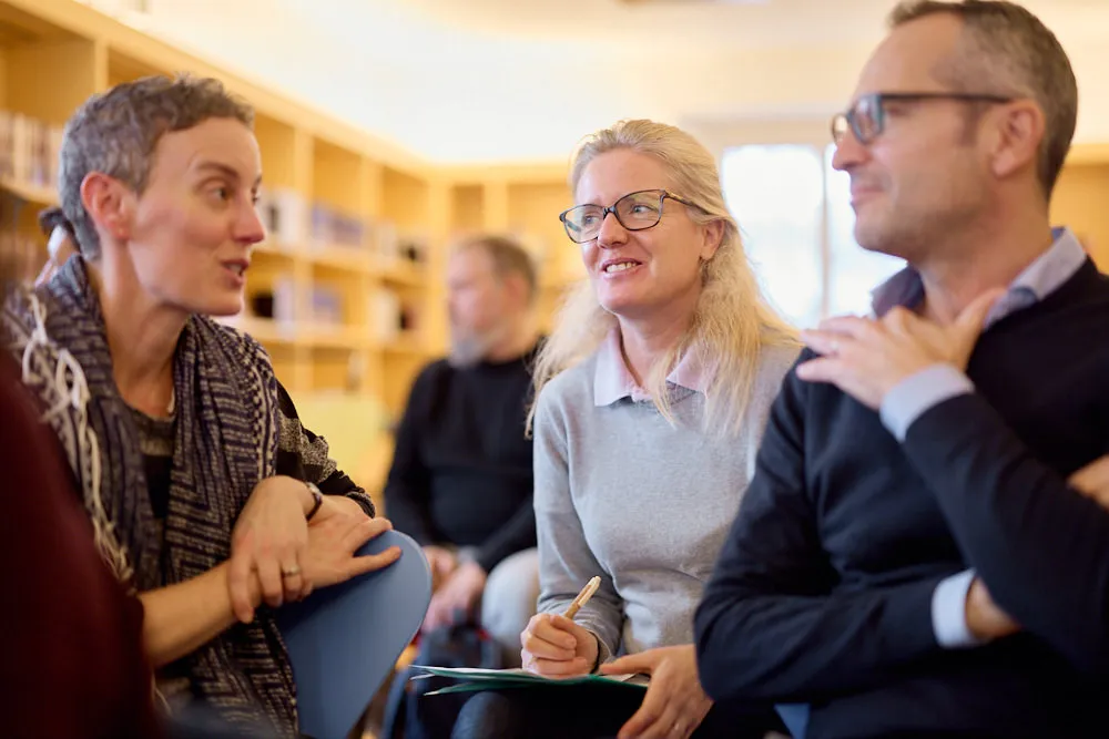 Zwei Frauen und ein Mann sprechen im Publikum miteinander.
