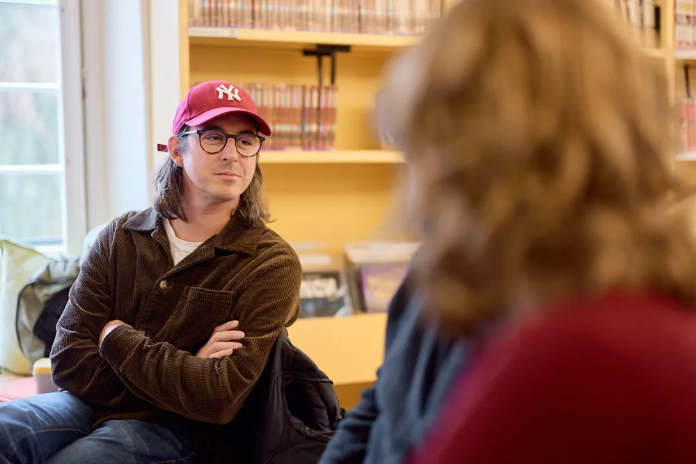 Ein Mann im Publikum hört anderen im Publikum gespannt mit verschlossenen Armen zu.