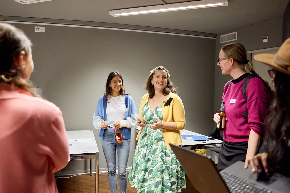 Eine Frau hält stehend eine Begrüssung. Frauen stehen um sie herum.