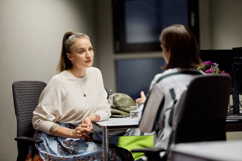 Zwei Frauen an einem Tisch sprechen miteinander.
