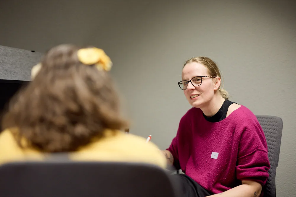 Zwei Frauen an einem Tisch sprechen miteinander.