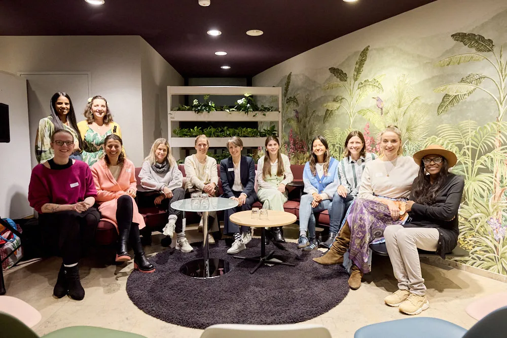 Eine Gruppe Frauen schauen lächelnd in die Kamera. Zwei Frauen stehen hinter zehn sitzenden Frauen.