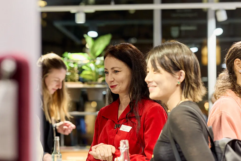 Zwei Frauen schauen gespannt und lächelnd in die gleiche Richtung.