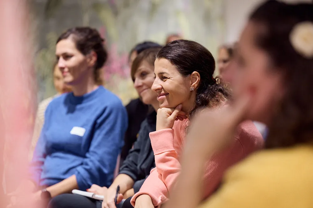 Frauen im Publikum hören gespannt und lächelnd zu.