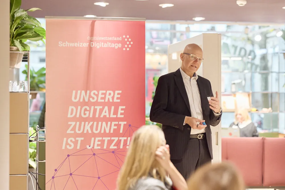 Ein Mann spricht zu einem Publikum vor einem Roll-Up.