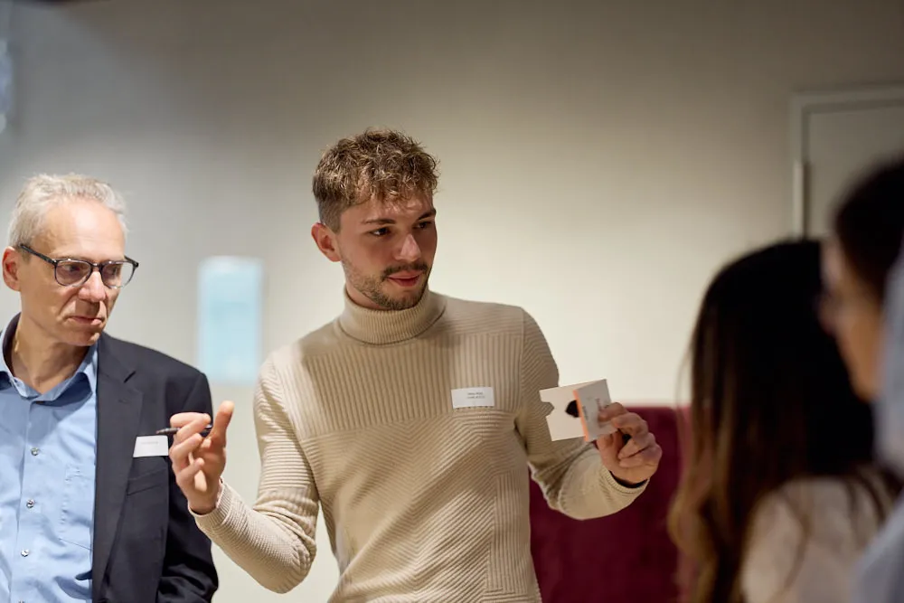 Ein Mann spricht zu zwei Frauen vor ihm. Hinter ihm befindet sich ein Mann, der auch zuhört.