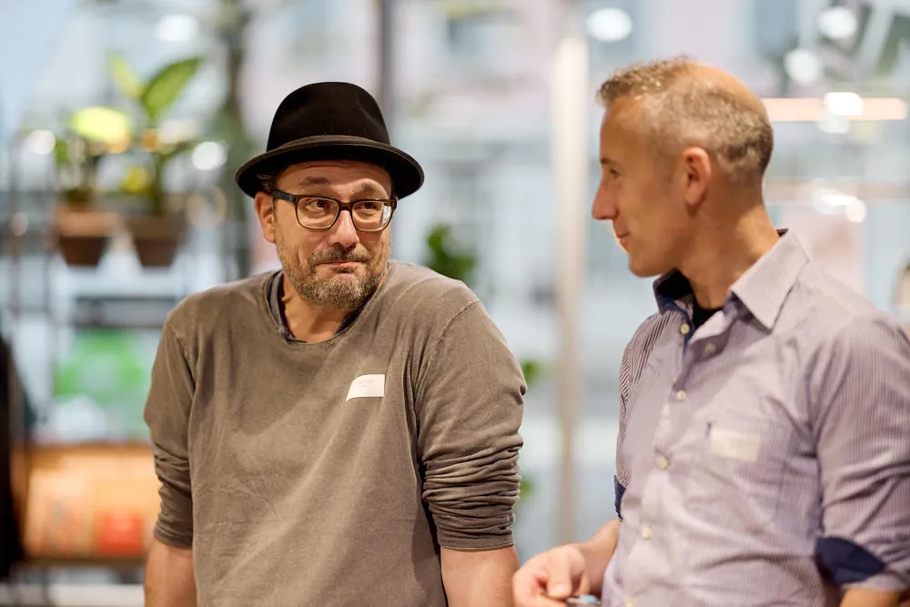 Zwei Männer stehen nebeneinander. Sie lächeln.