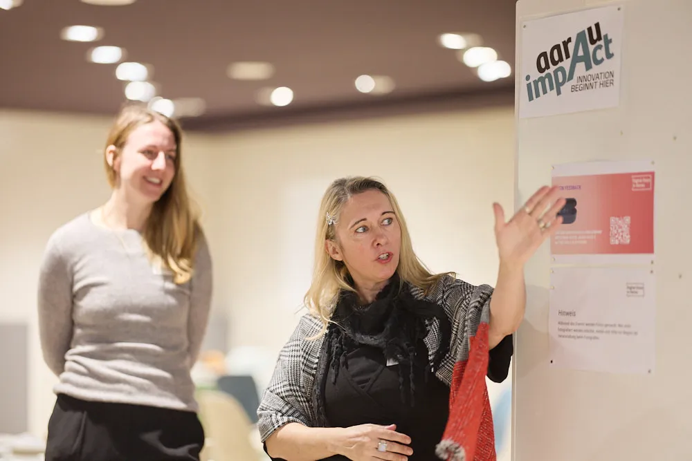 Eine Frau zeigt mit der Hand in eine Richtung. Hinter ihr steht eine andere Frau.