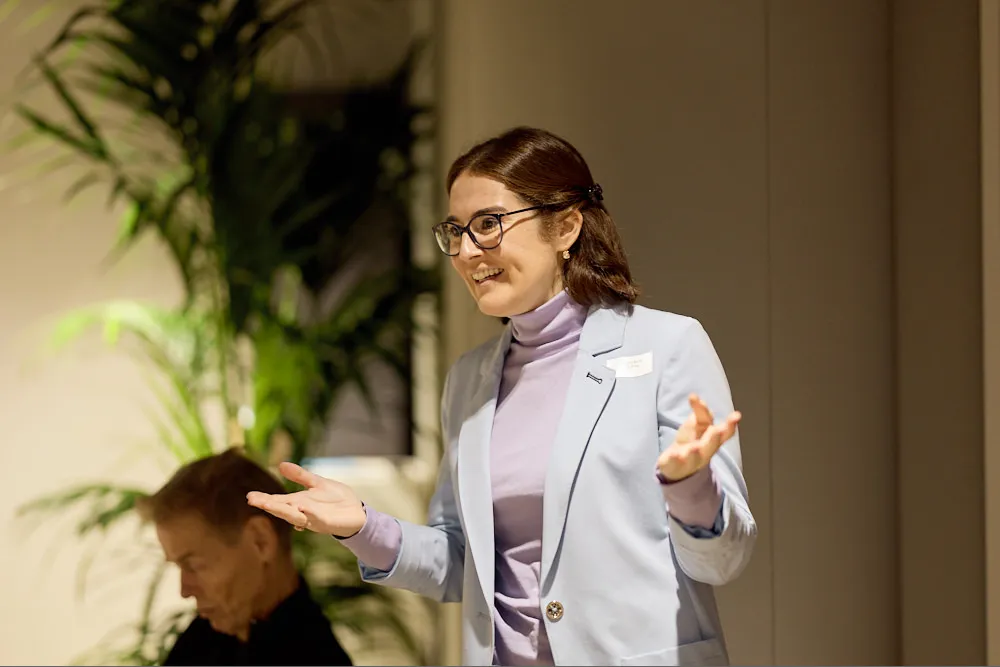 Eine Frau spricht zu einem Publikum. Sie lächelt und gestikuliert mit den Händen. 