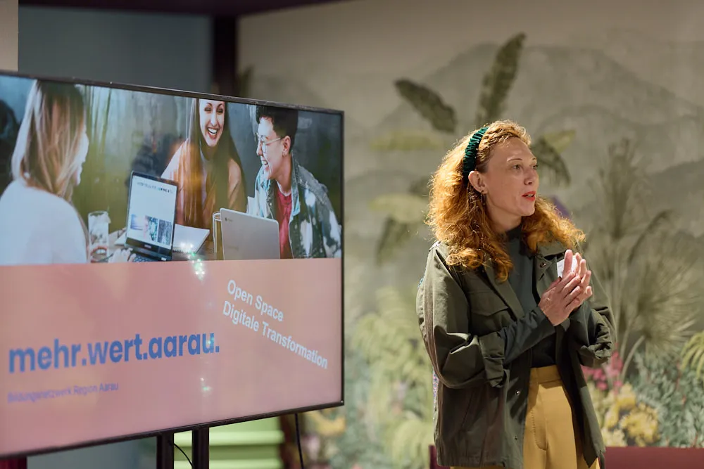 Eine Frau hält eine Präsentation vor einem Bildschirm.