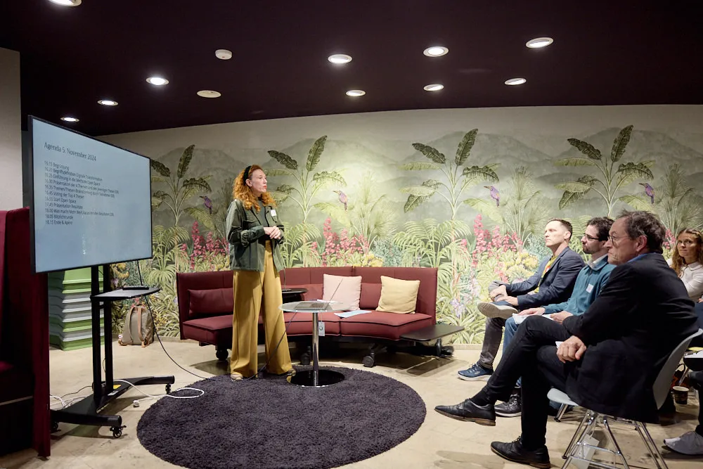 Eine Frau hält eine Präsentation vor einem Bildschirm vor einem Publikum.