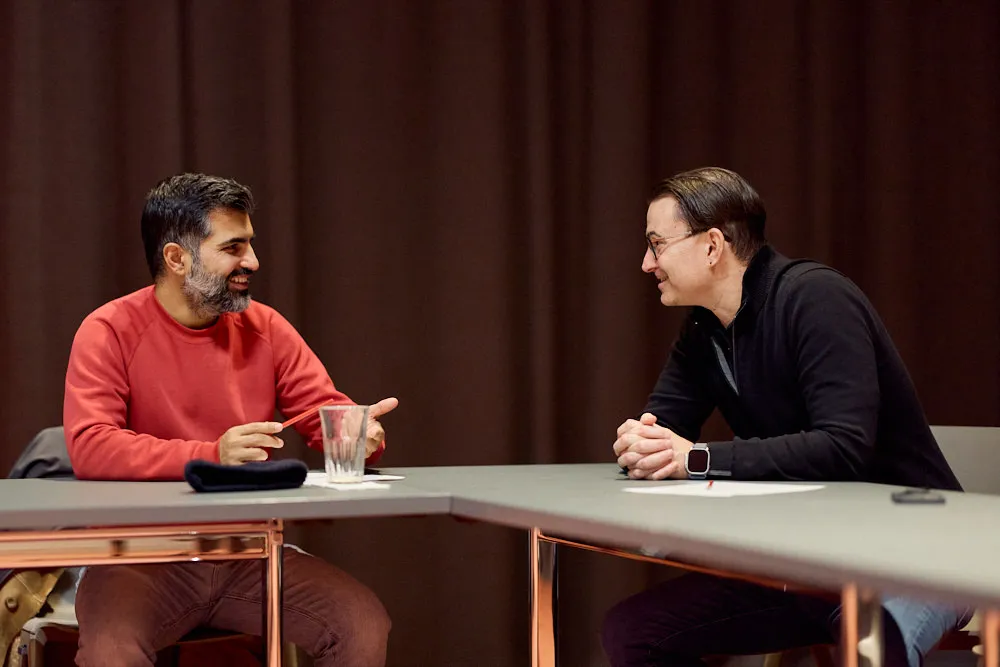 Zwei Männer sprechen miteinander. Sie lächeln sich an.