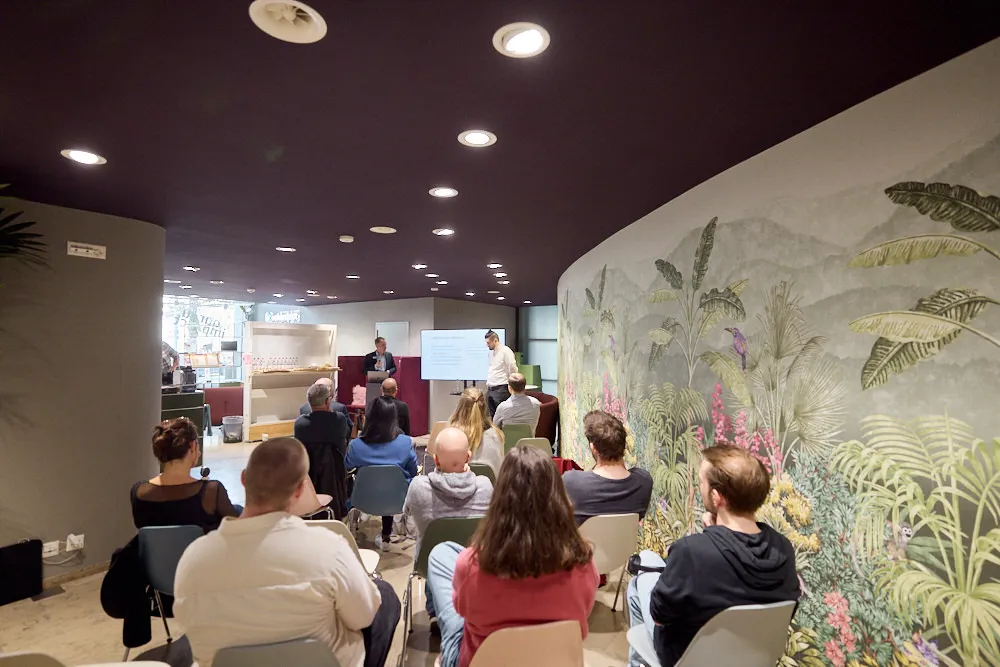 Zwei Männer halten vor einem Publikum eine Präsentation.