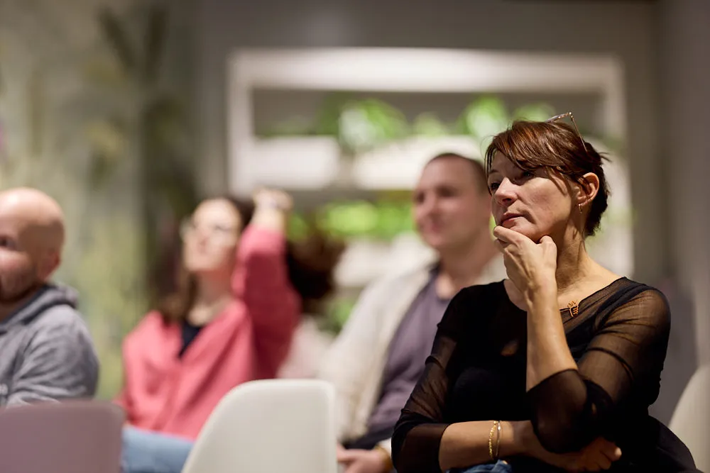Im Fokus ist eine Frau im Publikum. Sie hört gespannt zu.