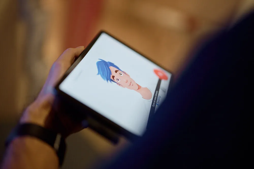Eine Person hält ein Tablet in der Hand. Auf dem Tablet ist eine illustrierte Person zu sehen.