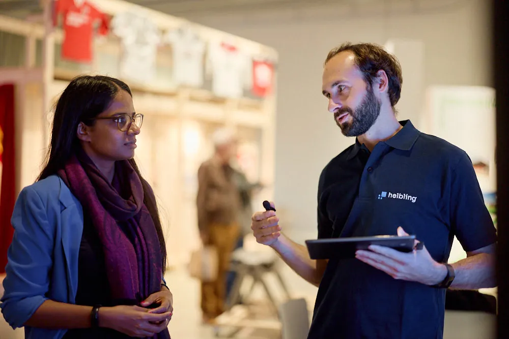 Eine Frau und ein Mann sprechen miteinander. Der Mann hält ein Tablet in der Hand.
