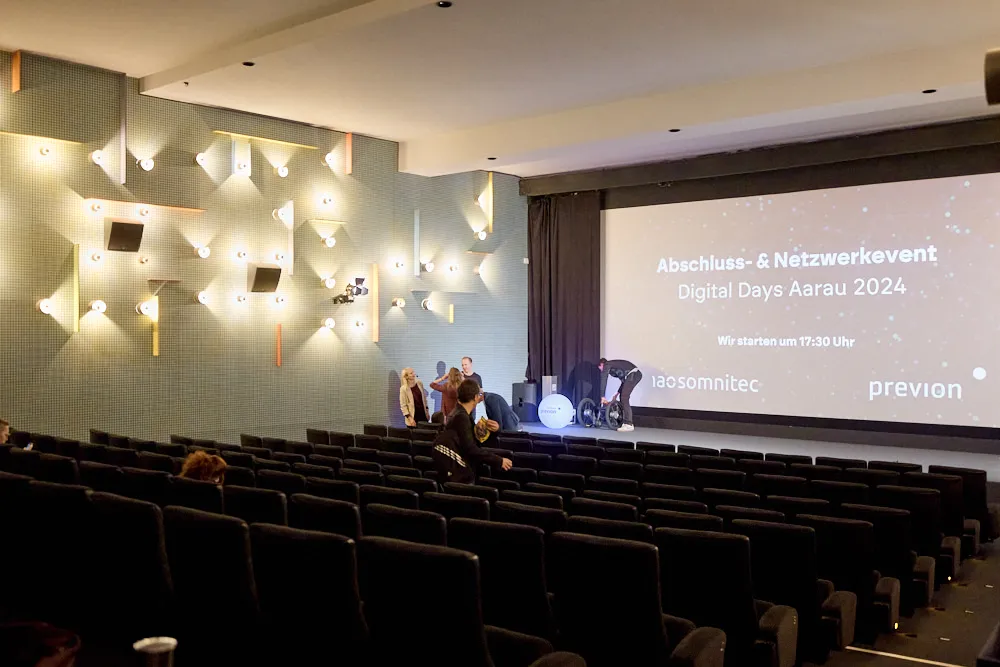 Ein fast leere Kinosaal. Auf der Leinwand wird eine Präsentation projiziert.