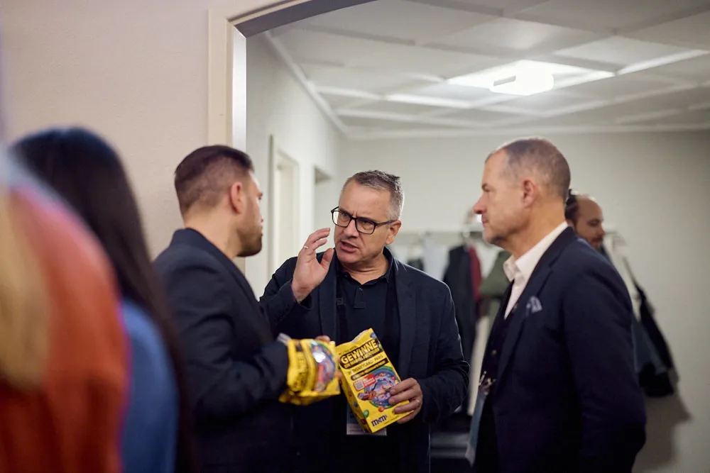 Drei Männer unterhalten sich und essen dabei Popcorn aus Popcorntüten.