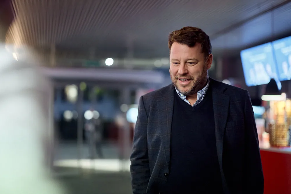 Ein Mann steht und lächelt in einem Kinogebäude.