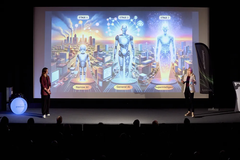 Zwei Frauen mit Headsets stehen vor der Kinoleinwand. Auf der Leinwand werde verschiedene Zukunftsmenschen in drei Stadien gezeigt.