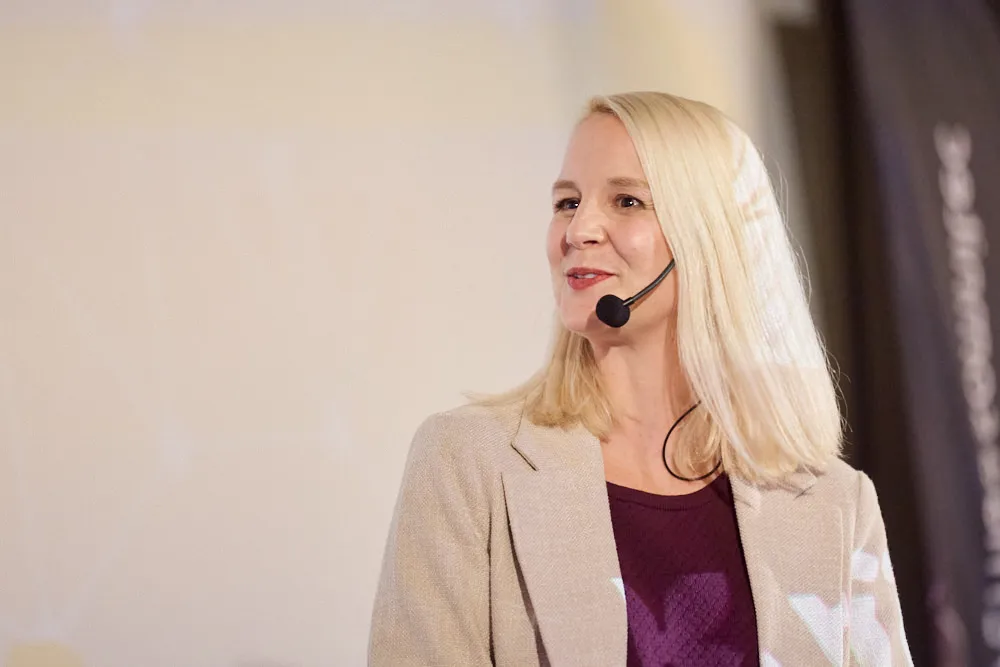 Eine Frau mit Headset spricht vor der Kinoleinwand.