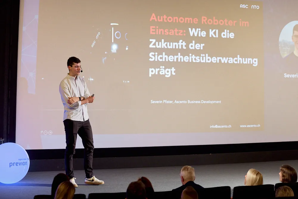 Ein Mann steht vor der Kinoleinwand und spricht zum Publikum im Kinosaal. Auf der Leinwand wird seine Präsentation projiziert.